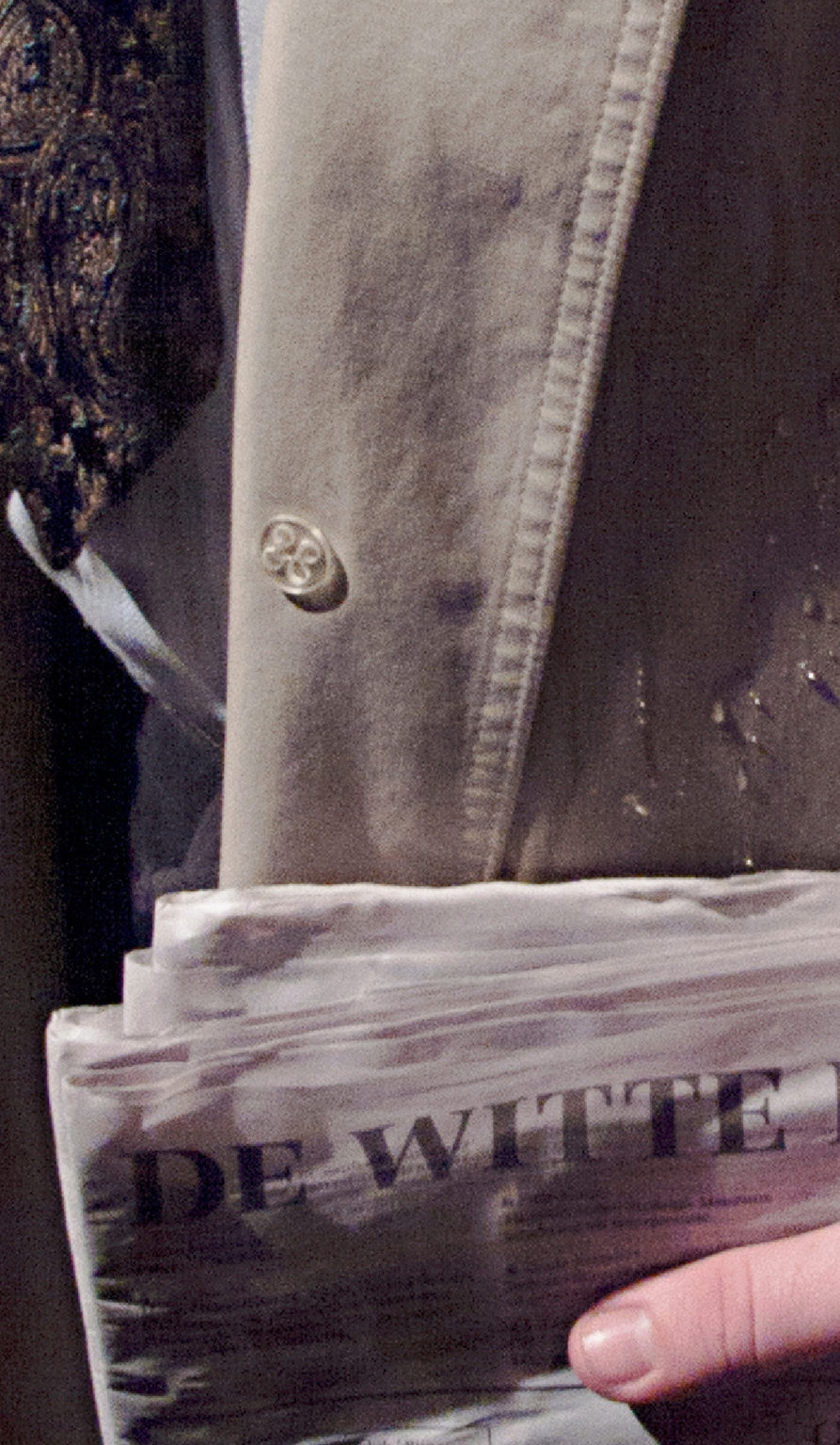 Homme en imperméable portant un journal