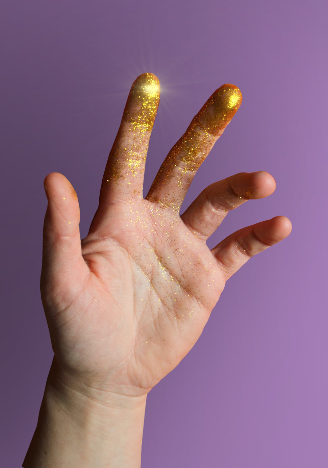 Main avec des paillettes dorées sur les doigts