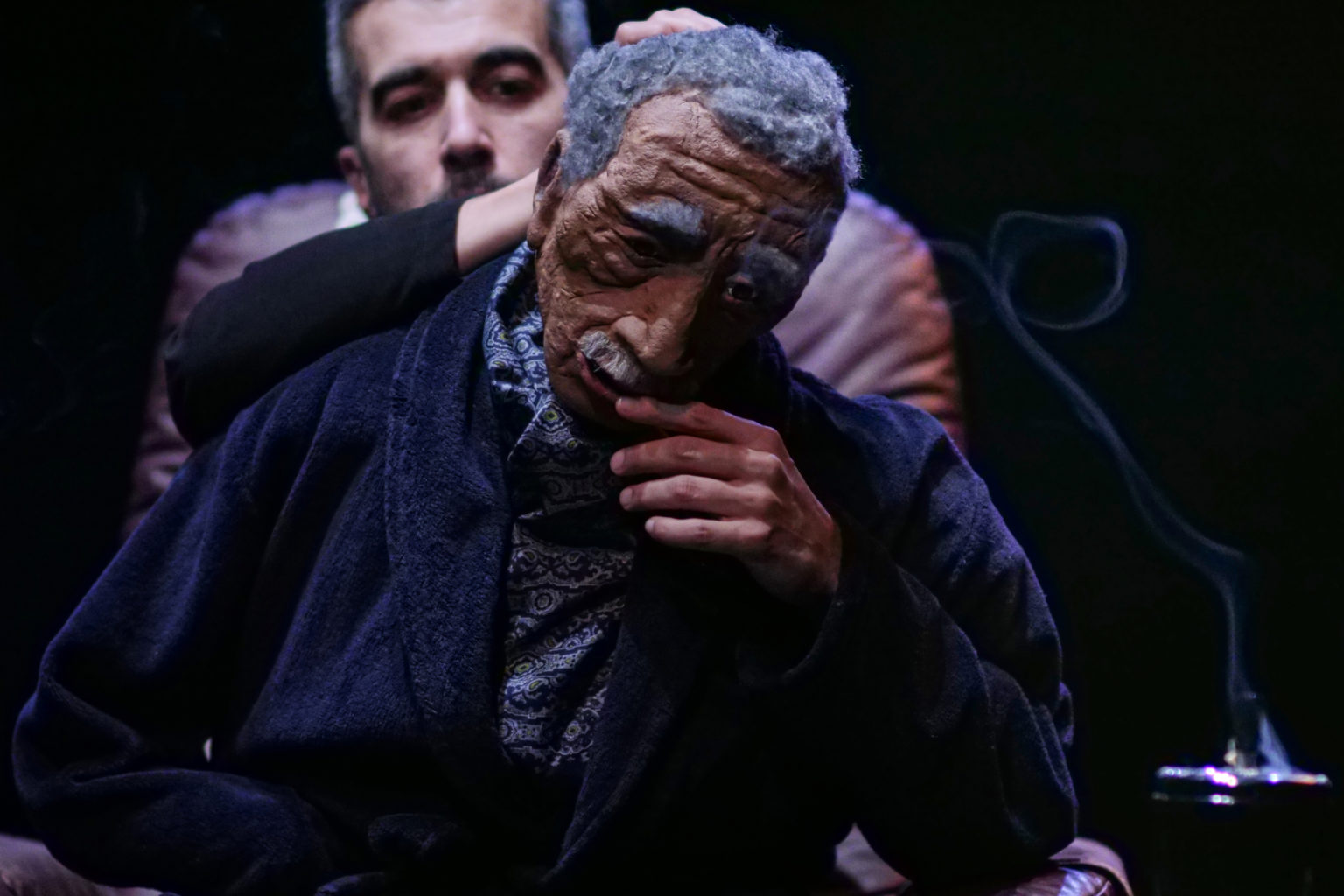 Photo du spectacle "Parti en fumée" où l'on voit le comédien Othmane Moumen manipuler la marionnette représentant son père.