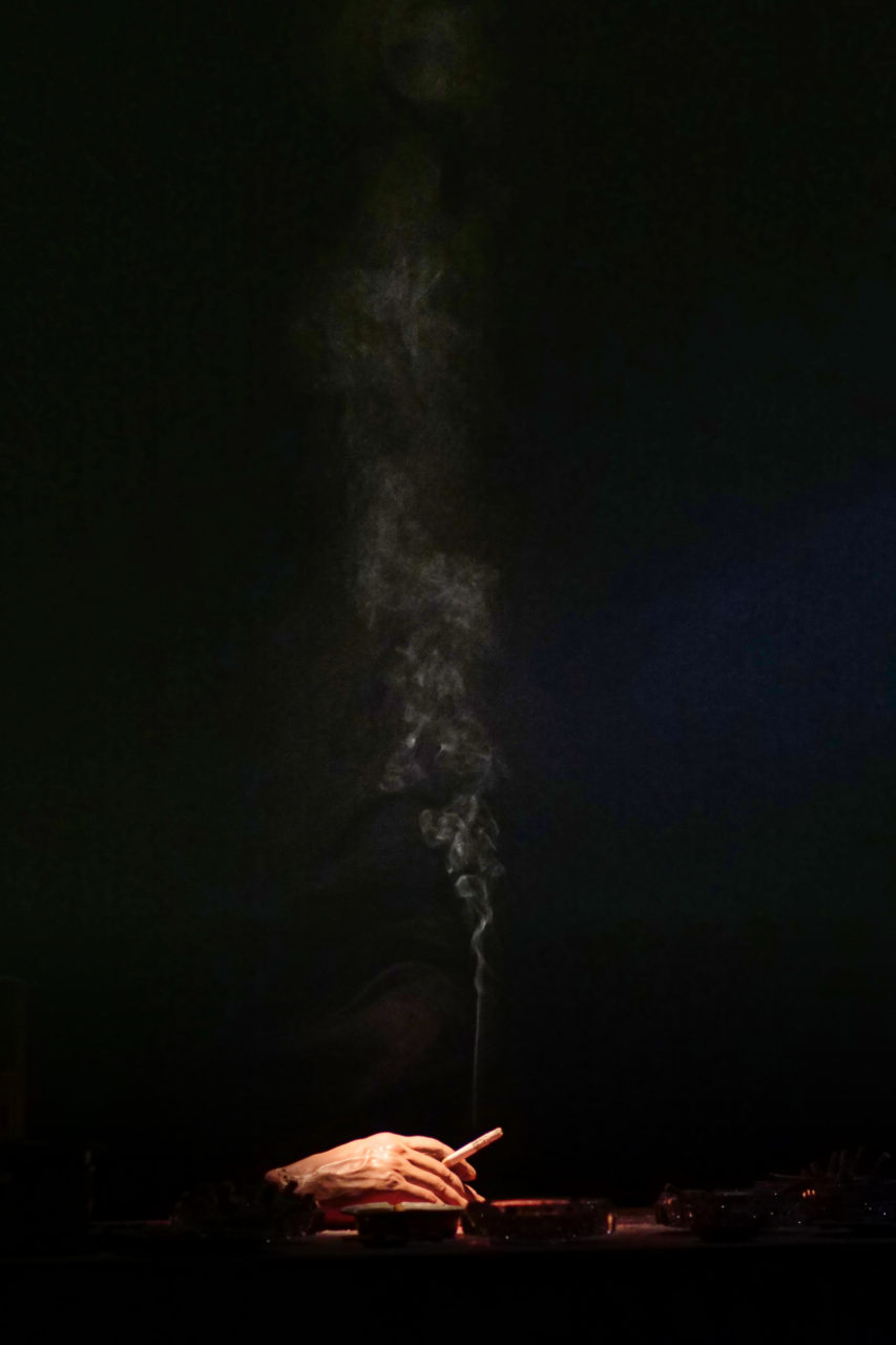 Photo du spectacle "Parti en fumée" où l'on voit une main qui fume une cigarette.