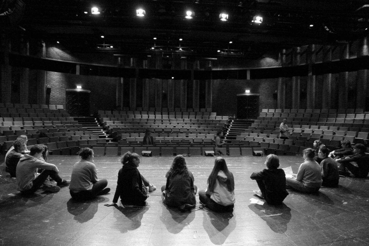 Groupe de jeunes gens assis sur une scène de théâtre