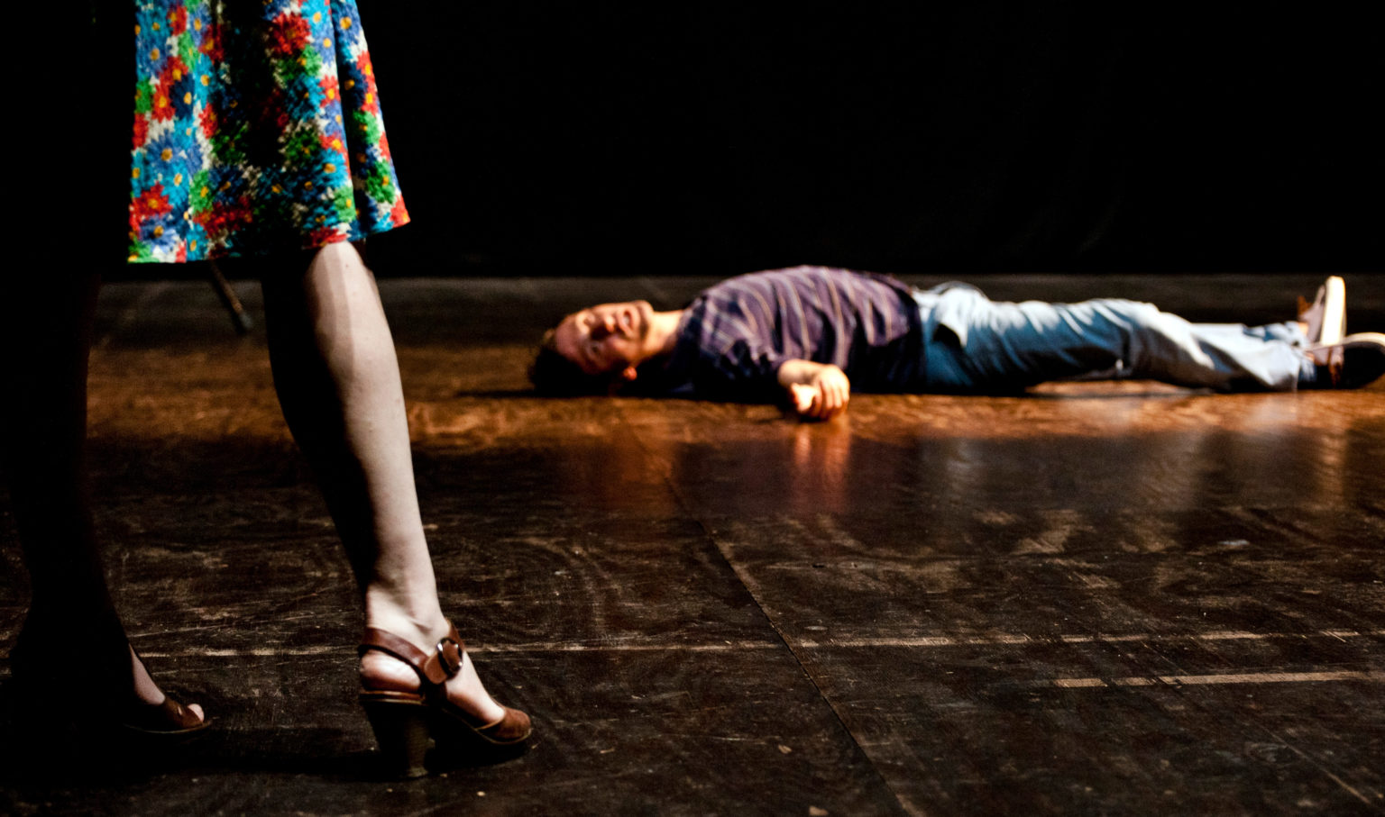 Jambes d'une femme en jupe et homme allongé sur le sol