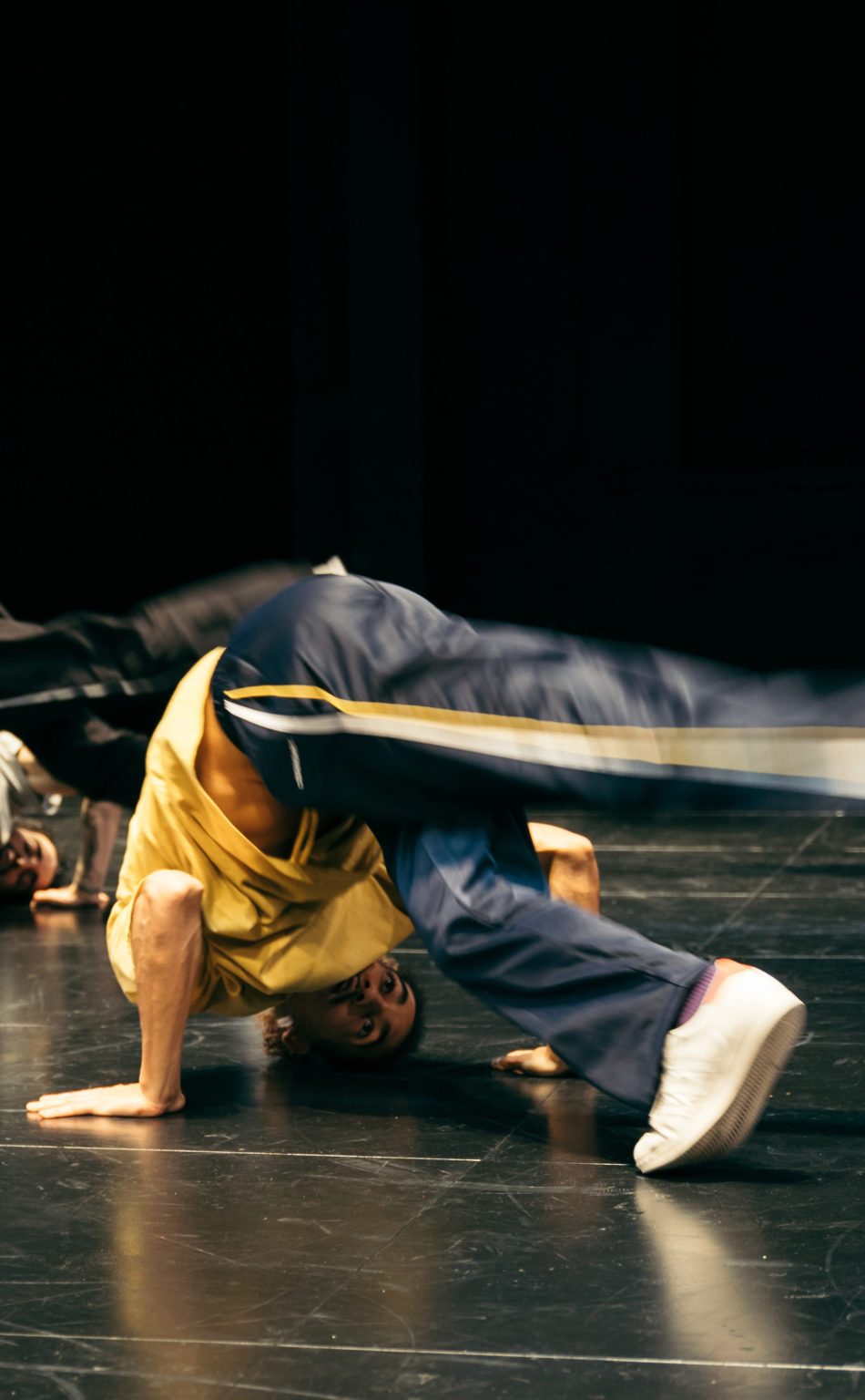 Deux danseurs effectuent un mouvement de breakdance, la tête au sol.