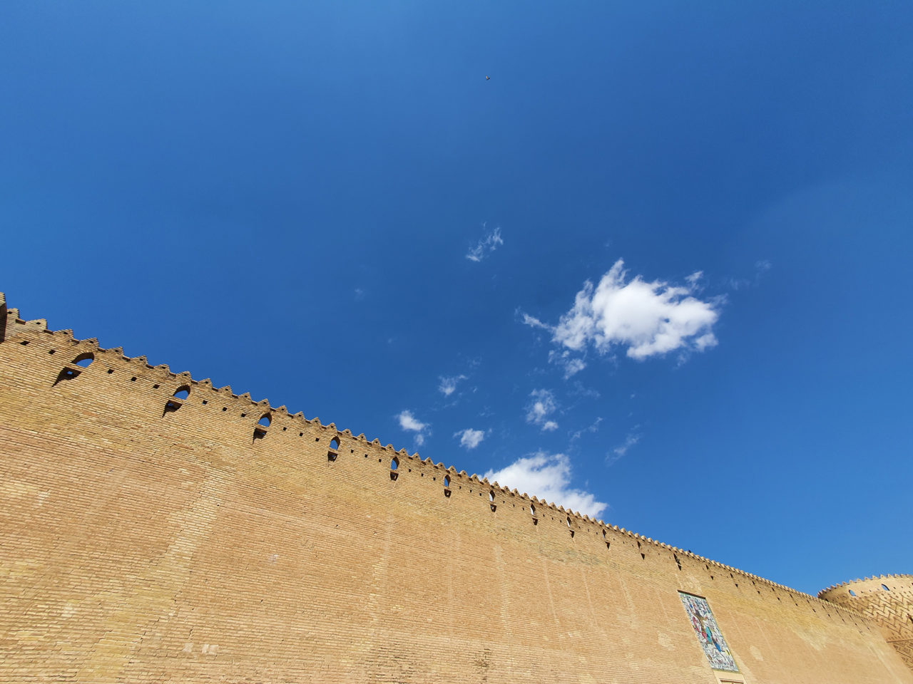 Photo d'un grand mur en Iran où l'on voit le ciel bleu et quelques nuages éparses