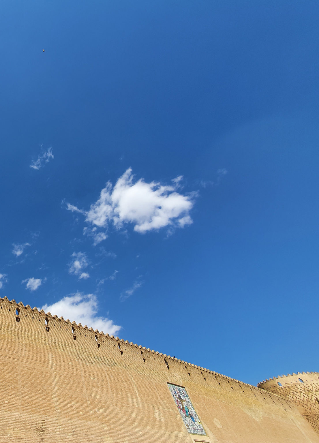 Photo d'un grand mur en Iran où l'on voit le ciel bleu et quelques nuages éparses