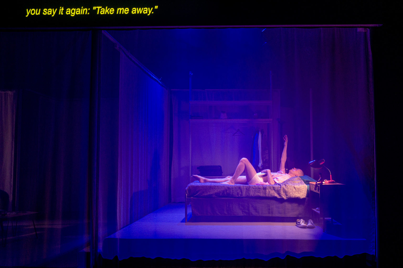 L'acteur Dany Boudreault est couché dans un lit dans le décor d'une chambre, une jambe repliée. Il lève un bras. Les tons sont bleus.
