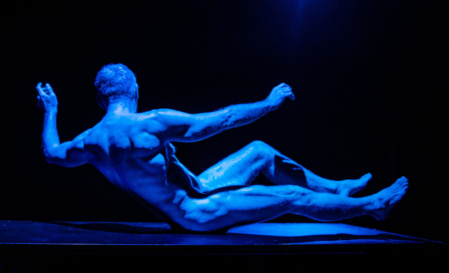 Thierry Smits est nu et assis. On voit son corps sculpté. Il est légèrement de dos.