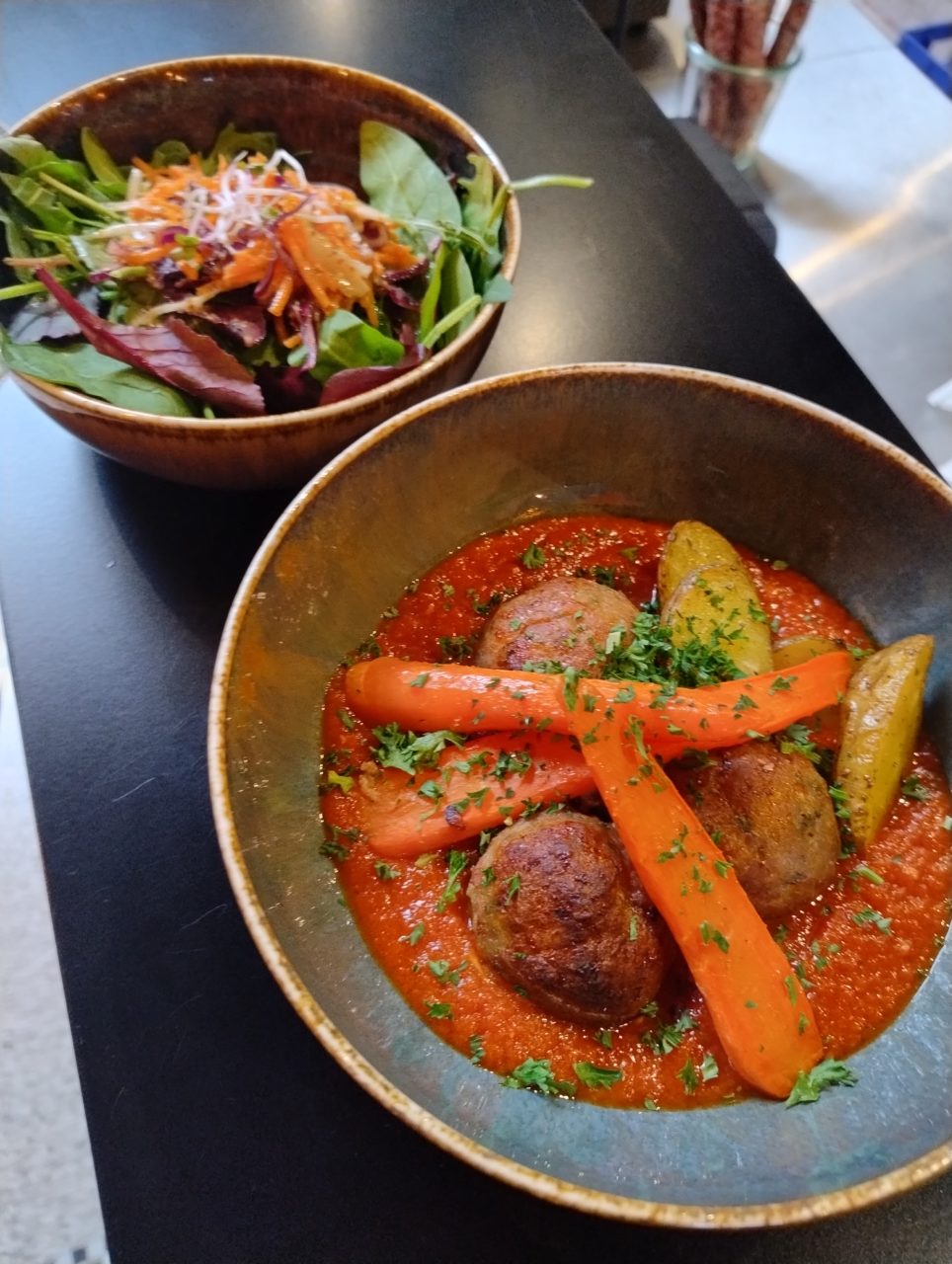 Photo d'un plat au Resto des Tanneurs, comprenant des boulettes sauce tomate, des pommes de terre et des carottes. Le tout accompagné d'une salade.