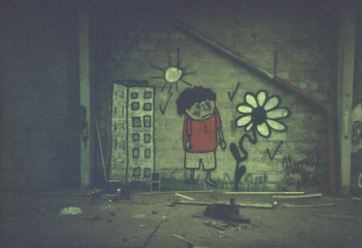 Fresque d'un enfant avec un t-shirt rouge accompagné d'un immeuble dessiné la gauche et d'un tournesol dessiné sur la droite.