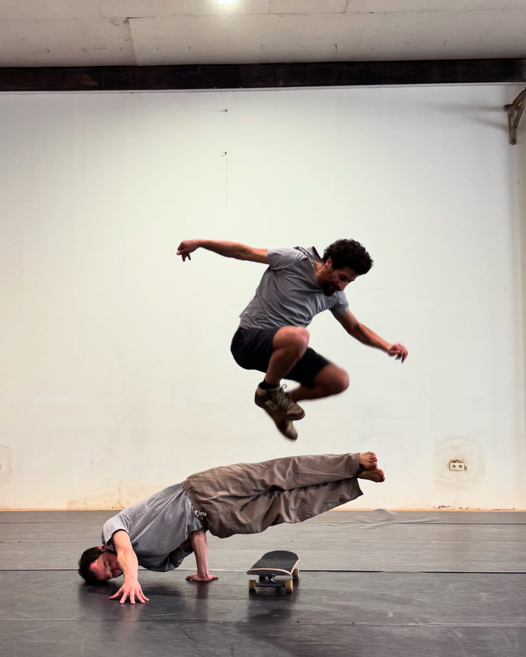 Deux hommes qui réalisent une figure de skate et de breakdance simultanément.