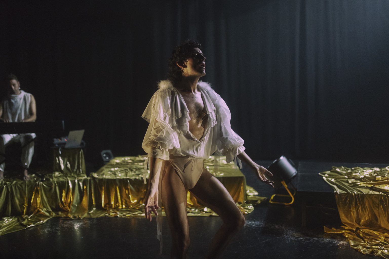 Alberto Cortés danse devant une scène avec un drap doré qui la recouvre.