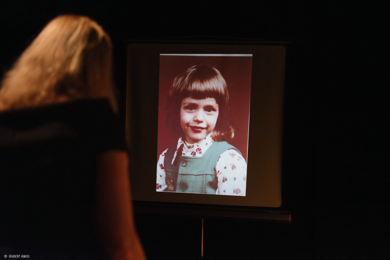 Geneviève Damas se tient debout face à un écran montrant la photo d'une petite fille.