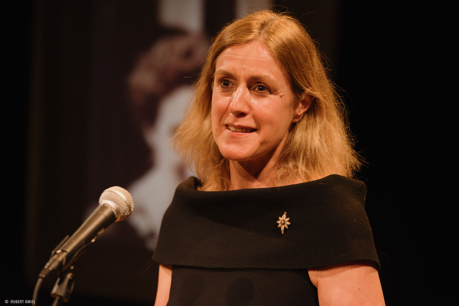 Geneviève Damas se tient debout derrière un micro.