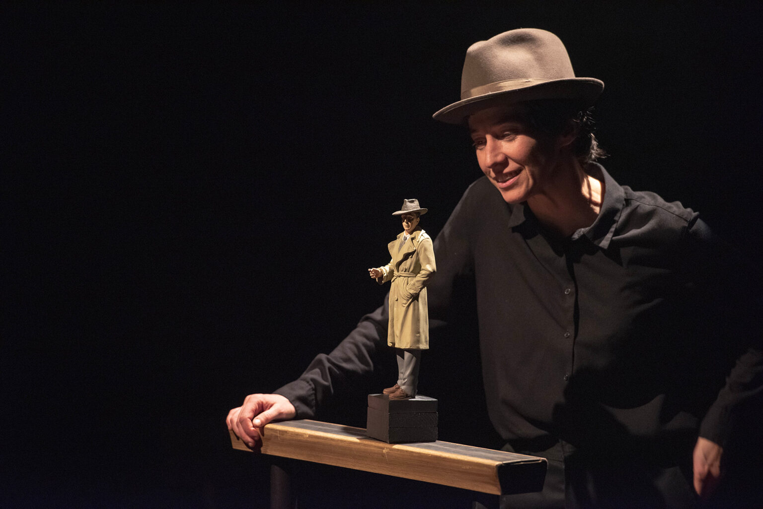 L'atrice Marie Delhaye porte un chapeau, type ranger. Devant elle, une figurine d'homme portant un imperméable beige et un chapeau similaire. Certainement un enquêteur.