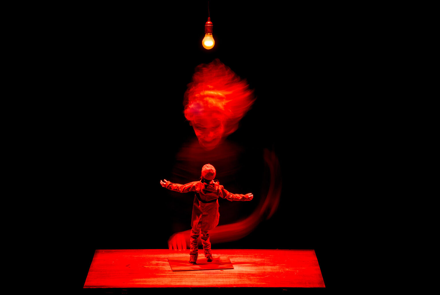 Sur la table, sous une lumière rouge, se tient la figurine de Raskolnikov, de dos. Derrière lui, l'un des acteurs porte un masque de vieille personne. Il fait peur. Il bouge et est un peu flou.