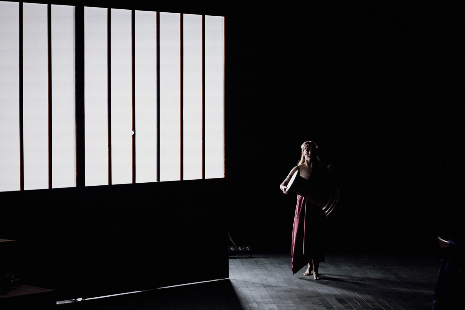 Une actrice s'avance dans la pénombre. Elle porte une toge.