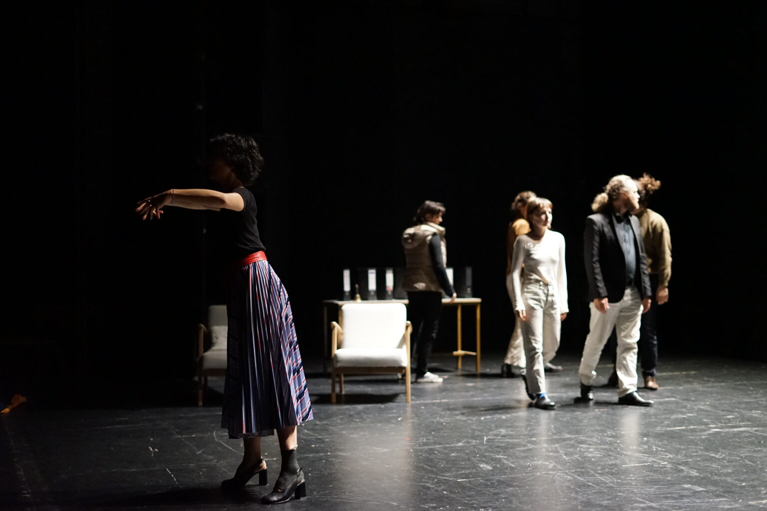 Les participants de la chorale se baladent dans l'espace. La cheffe de choeur est sur le côté.