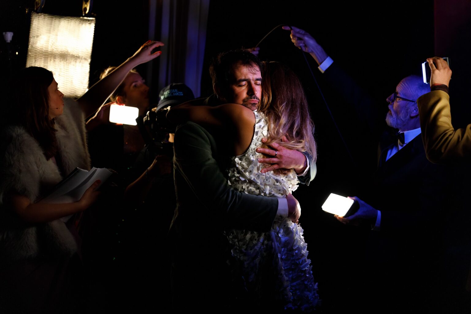 Un acteur et une actrice se prennent dans les bras. Ils sont dans la semi-obscurité. Autour d'eux, des acteurs les filment avec leurs smartphones.