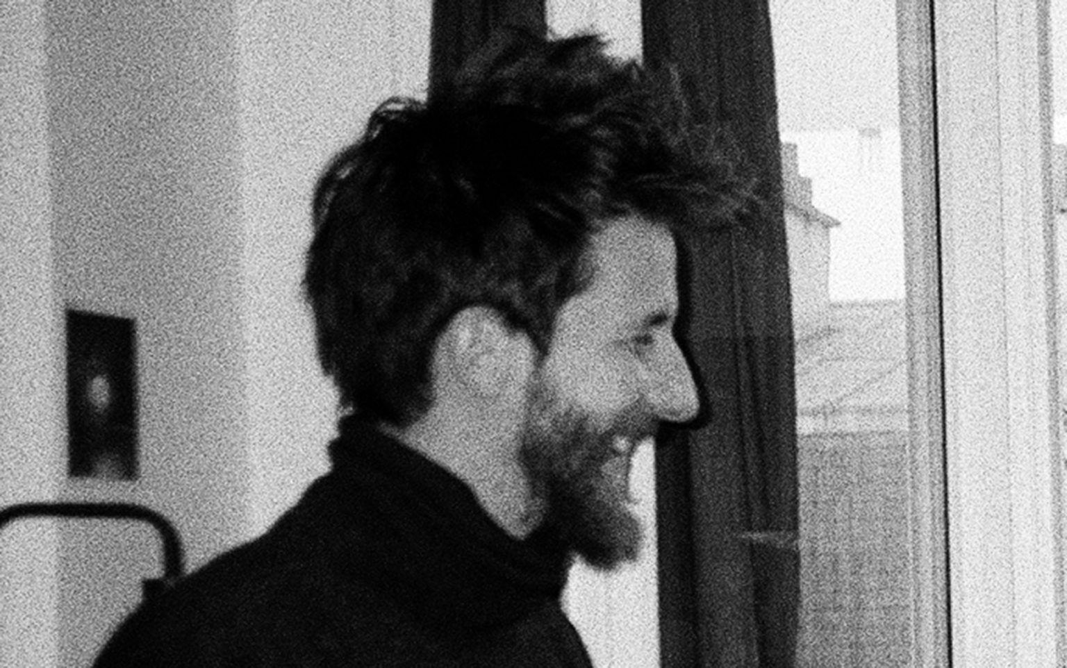 Portrait en noir et blanc de Gabriel Sparti. Il est de profil, sourit et porte un pull.