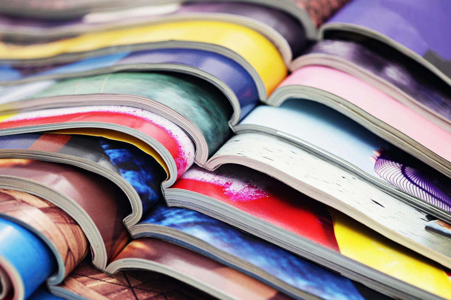 Pile de magazines ouverts en leur milieu, de toutes les couleurs.