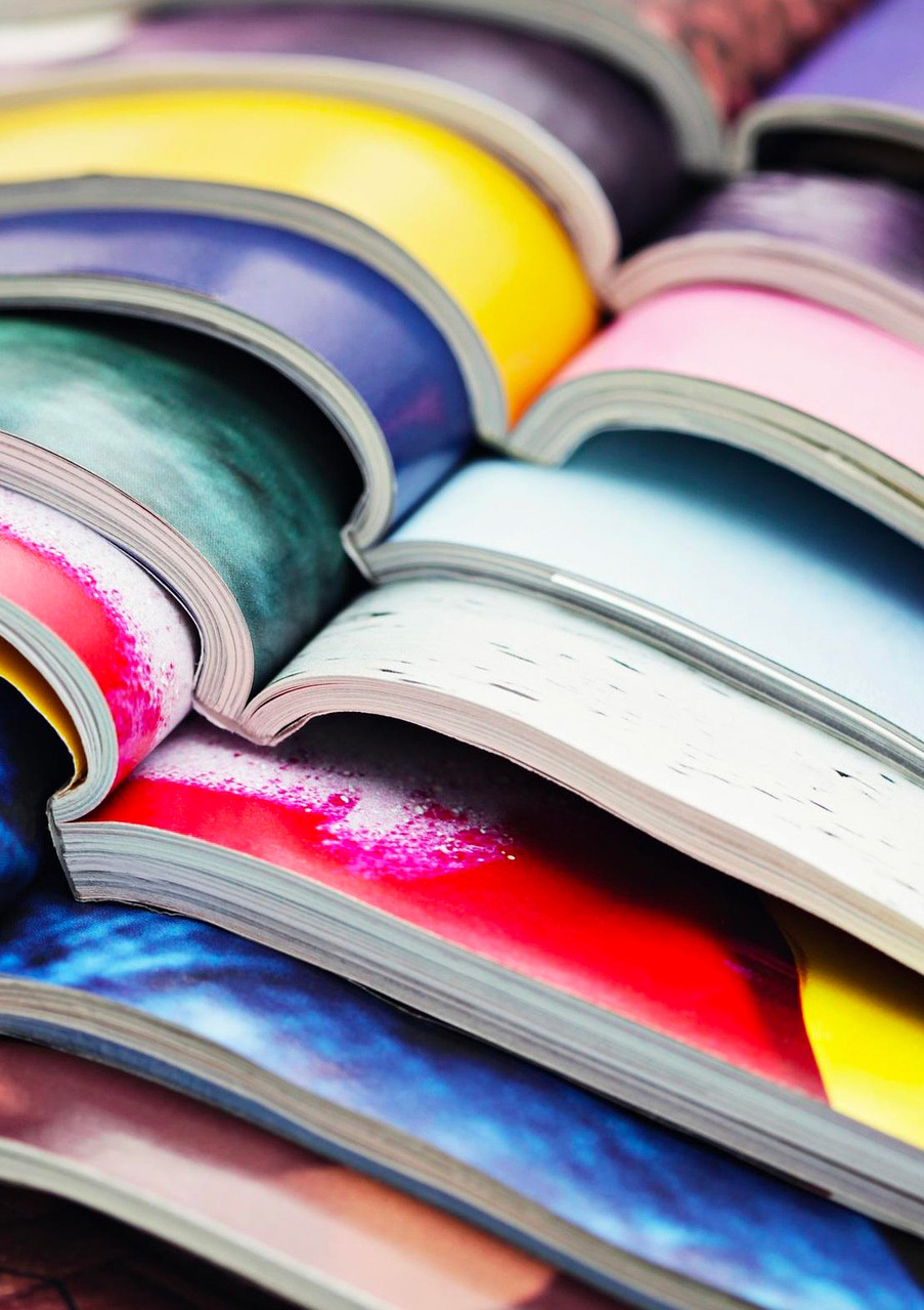 Pile de magazines ouverts en leur milieu, de toutes les couleurs.