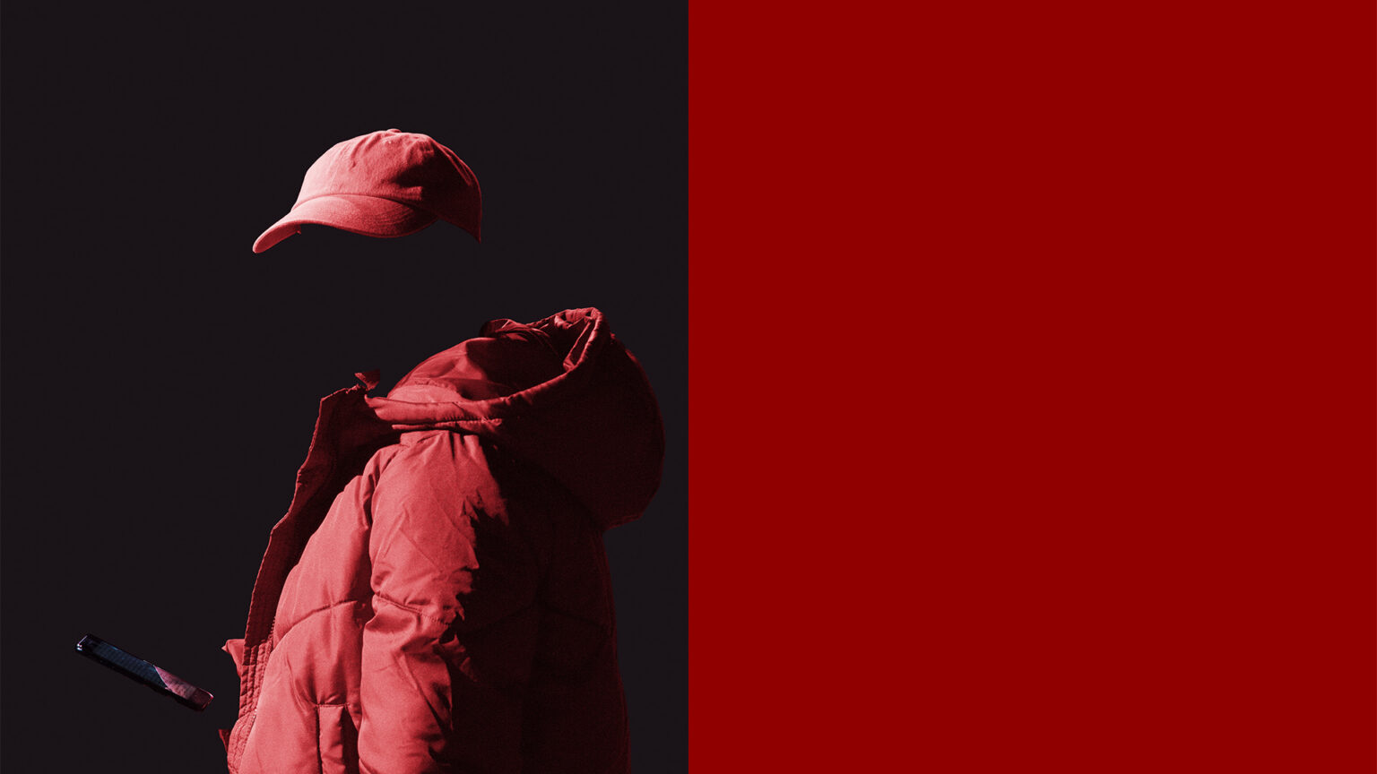 Le visage d'une personne entièrement vêtue de rouge se fond dans le noir de l'arrière plan. Toute la moitié droite de l'image est rouge monochrome.