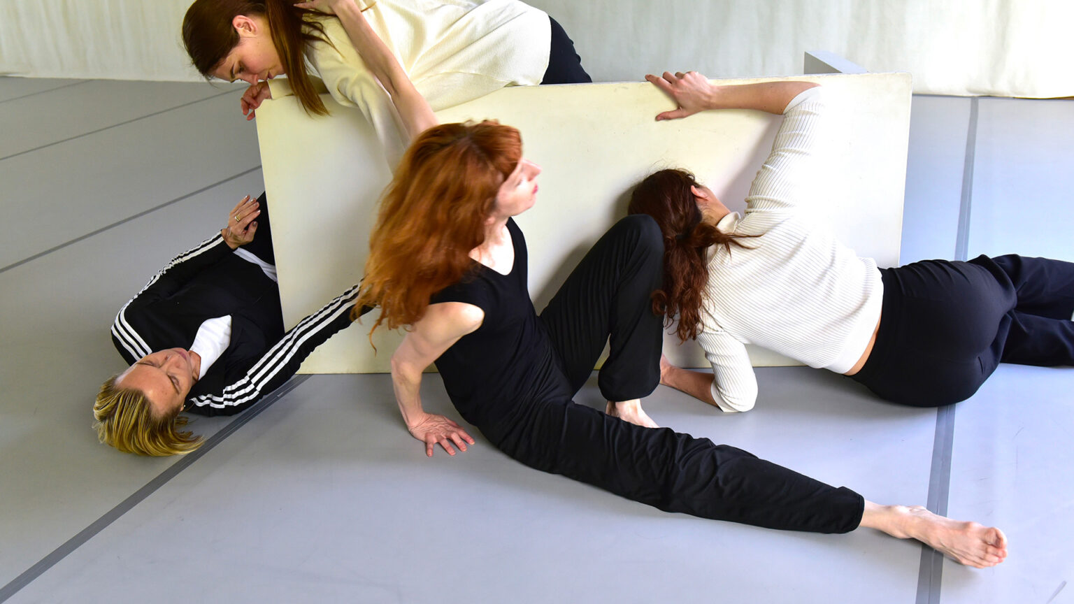 Les 4 interprètes de Lignes de fracture (Caterina Campo, Michèle Noiret, Lise Vachon, Léa Vinette) sont installées de part et d'autres, en position couchées ou assises, d'une table blanche qui repose sur son bord et non sur ses pieds.
